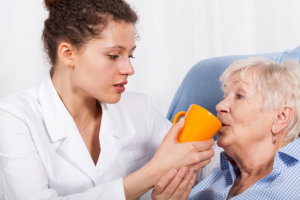 Assisting elder woman drinking water