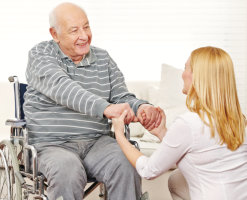 Elderly man in wheelchair with female staff