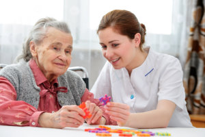 Elder woman and female staff playing puzzle